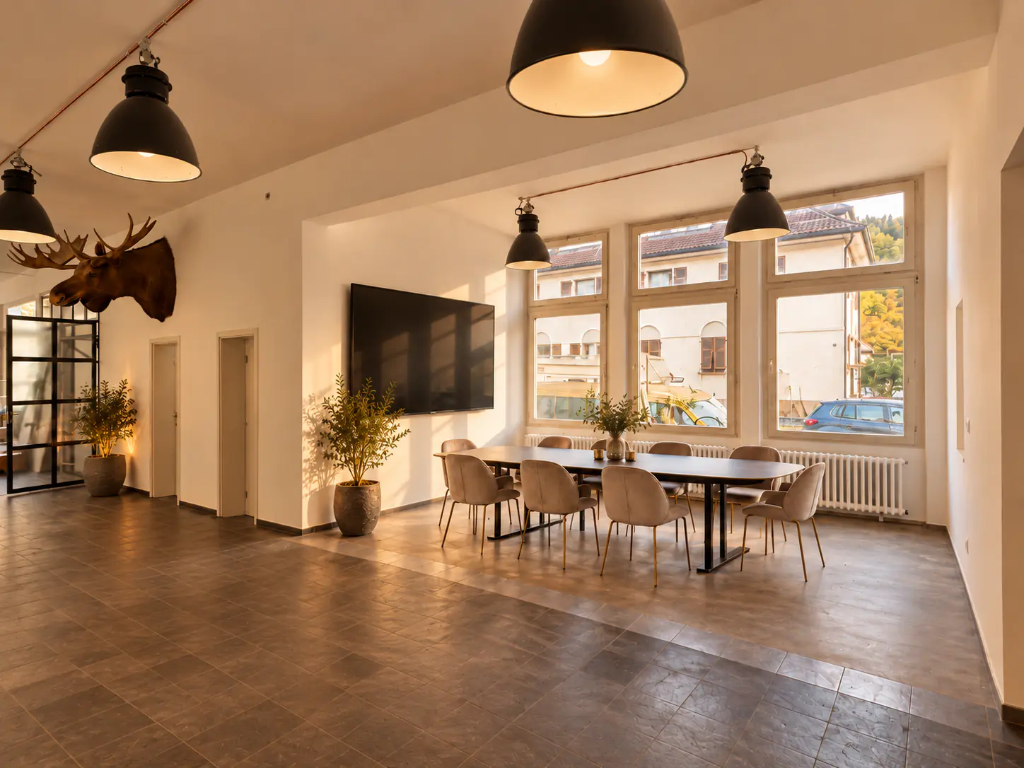 Meeting room with a conference table, large screen and tall windows