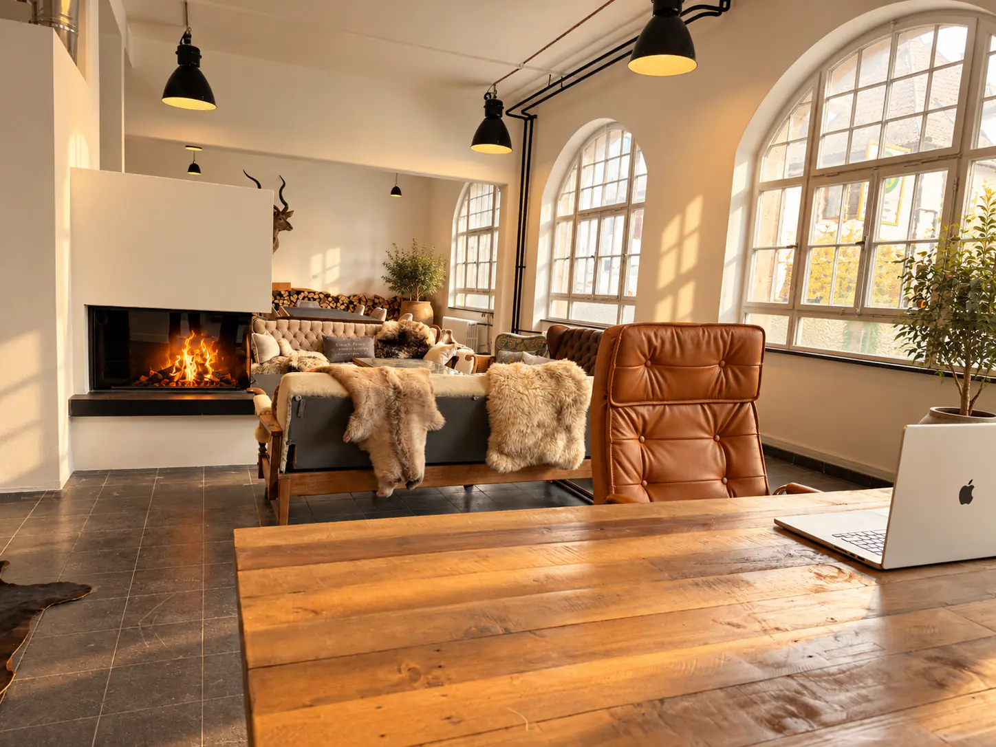 Desk at a wooden table looking towards the fireplace and arched windows
